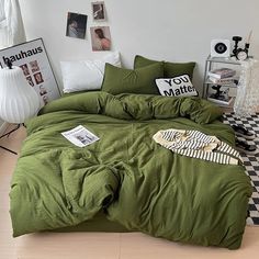 a bed with green sheets and pillows in a room next to pictures on the wall