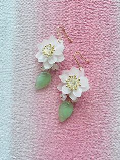 These Cherry Blossom earrings are a delightful addition to any jewelry collection, with their intricate handmade design and delicate white Sakura flowers. The earrings feature a beautiful blend of colors and textures, with flower buds and leaves dangling gracefully from the main flower. The aesthetic earrings are inspired by traditional Japanese style, incorporating the timeless beauty of cherry blossoms into their design. The Kawaii earrings are perfect for anyone who loves cute and charming ac Cherry Blossom White, Japanese Earrings, White Sakura, Cherry Blossom Earrings, Design Japonais, Earrings Kawaii, Aesthetic Earrings, Sakura Flowers, Kawaii Earrings