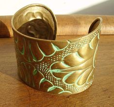 A very cool handmade brass cuff bracelet, decorated with a repousse pattern infilled with a verdigris green type patina. Not sure exactly where this originates from, it's quite Arts & Crafts in style, but more modern than that - possibly Eastern or Egyptian. Measuring approximately 1 7/8" high and 2 5/8" wide, could be expanded or reduced in diameter if preferred - dating to circa the 1970s or 1980s. Artisan Green Cuff Bangle Bracelet, Vintage Green Bracelet With Patina, Handmade Green Brass Bracelets, Handmade Green Brass Bracelet, Handmade Brass Bracelets In Green, Artisan Green Patina Bracelets, Artisan Green Bracelet With Patina, Green Artisan Bracelet With Patina, Green Patina Bangle Bracelet