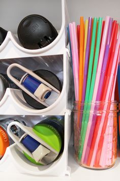 there are many cups and pencils in the container on the shelf next to each other