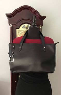 "Lauren Ralph Lauren  Coated Leather Tote  Black Silver Hardware  Double handles with 9\" Drop D-Ring hangtag Signature LRL embossed on front 2 Interior slip pockets 1 very large interior pocket with snap closure  1 large wall zip pocket  Signature Lauren Ralph Lauren lining with Key fob Zip closure  Originally priced over $180 Measures approximately: 15\" L-Top 11\" L Bottom 9.5\" H 4.25\" W Very good-excellent. Disclosure** small amount of rubber edge on handle has  come off but, edge is seale Forest City, Black Leather Bags, D Ring, Key Fob, Large Wall, Leather Coat, Silver Hardware, Lauren Ralph Lauren, Leather Tote