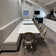 a long table and chairs in a room with white cupboards on either side of the wall