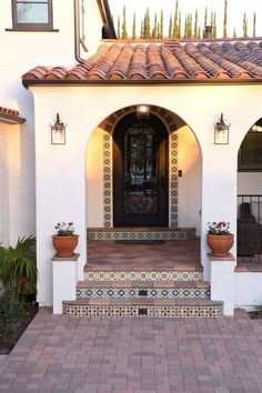 the front entrance to a house with potted plants