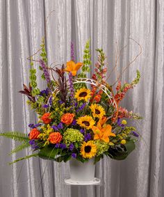 a white vase filled with lots of colorful flowers