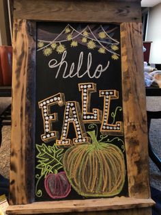 a chalkboard sign with the words hello fall written on it in front of a table