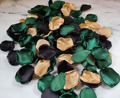 green and black satin flower petals on a marble counter top with gold foiled edges