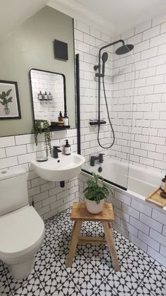 a white bathroom with black and white tiles on the floor, toilet, tub, sink and shower