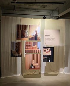 an exhibit with several pictures on the wall and behind it is a white drape