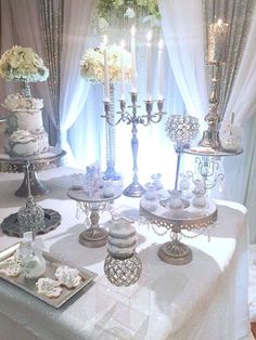 a table topped with lots of cake covered in white frosting next to a tall candelabra filled with flowers