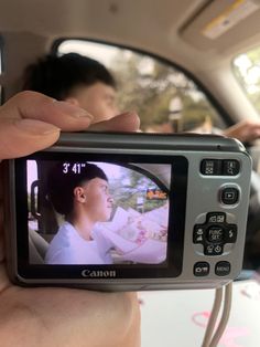 a person is holding up a camera to take a photo in the back seat of a car