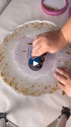 a person is making something out of paper and gold flakes on a white table