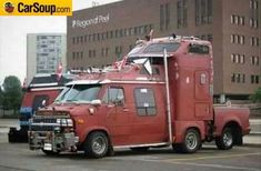 an old red truck is parked in front of a large building with flags on it