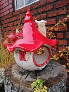 a red and white birdhouse sitting on top of a tree stump in front of a brick building