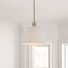 a white lamp hanging from a ceiling in a room next to a table and chairs