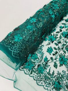 green lace with flowers and leaves on the bottom is laying on top of a piece of fabric