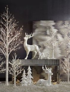 white christmas trees and deer on display in front of a black wall