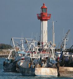 several boats in the water near a light house