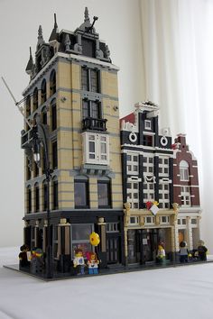 a lego model of a building with people standing in front of it on a table