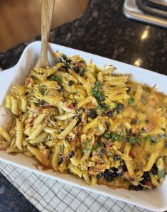 a casserole dish with pasta and olives in it, on a table