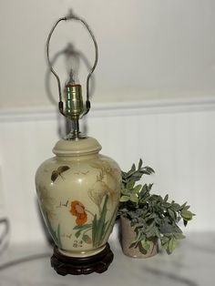 a vase sitting on top of a table next to a potted plant and a lamp