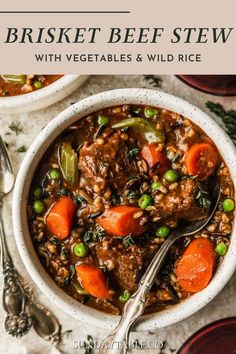 two bowls filled with beef stew and carrots on top of a white tablecloth