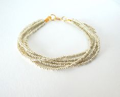 "This bracelet is made with a very soft gold color and the bead has a metallic finish, which makes the light reflect on it in a lovely way. We have sold hundreds if not thousands of these bracelets, for bridesmaids, brides, gifts, and for stylish girls who want to have a timeless piece of jewelry. It is chic and it has such a polished look! Plus, very affordable. It has 5 strands and you can choose size. More items in soft/pale gold: https://www.etsy.com/shop/StephanieMartinCo?ref=seller-platfor Gold Beaded Bracelets With Tiny Beads For Party, Gold Multi-strand Beaded Bracelet As Gift, Multi-strand Bracelet With Gold Beads As Gift, Multi-strand Gold Beads Bracelet Gift, Gold Bracelets For Party, Elegant Gold Bracelets With Silver Beads, Gold Bracelets With Tiny Beads For Party, Gold Bracelet With Tiny Beads For Party, Gold Multi-strand Beaded Bracelet