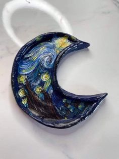 a ceramic sculpture of the starry night in the shape of a half moon on a white surface