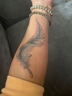 a woman's arm with a feather tattoo on it