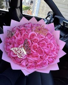 a bouquet of pink roses and butterflies in the front seat of a car with happy birthday written on it