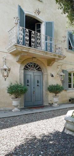 an image of a house with blue shutters on the front door and balcony above it