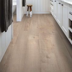 a kitchen with white cabinets and wood flooring on the walls, along with a wooden stool