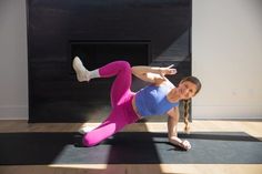 a woman doing an exercise on a yoga mat in front of a fire place with her legs spread out