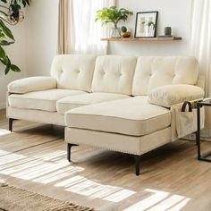 a living room with a white couch and coffee table in front of a window on top of a hard wood floor