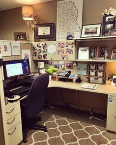 an office with a desk, computer monitor and pictures on the wall above it's cubicle