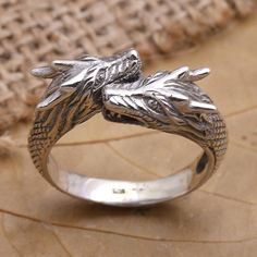 Mythical and mysterious Budiharta's silver ring features two dragons wrapped up in romance. The Balinese artisan hand crafts the wrap-style ring from sterling silver engraving the precious metal with a raised pattern that resembles dragon scales. Collectible Dragon Design Jewelry Ring, Collectible Dragon Design Ring, Dragon Design Ring Jewelry Gift, Dragon Design Ring Jewelry For Gift, Adjustable Dragon Design Ring, Adjustable Dragon Design Jewelry Ring, Medieval Engraved Jewelry For Anniversary, Unique Snake Ring With Dragon Design Gift, Adjustable Sterling Silver Dragon Jewelry