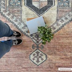 a person standing in front of a rug with a plant on it and a book