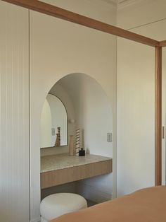 a bed sitting under a mirror next to a white cabinet with a vase on it