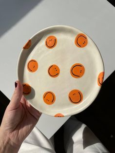 a person holding a plate with orange smiley faces on it, in front of a white background