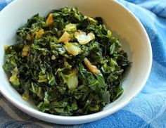 a white bowl filled with greens on top of a blue towel