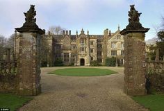 an old castle with two gates leading into the front yard and entrance to another building