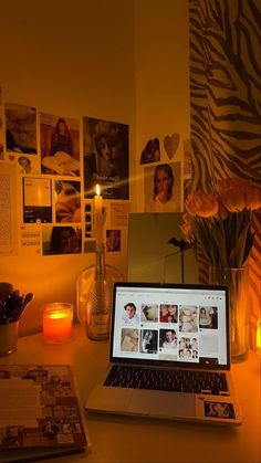 an open laptop computer sitting on top of a desk next to a vase filled with flowers