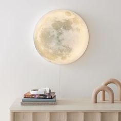 the moon lamp is mounted on the wall above some books and other items in front of it