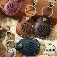 four leather keychains with the letter v on them are sitting next to each other