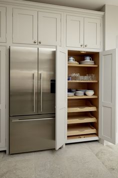 a stainless steel refrigerator freezer sitting inside of a kitchen next to white cupboards