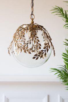 a glass ball hanging from a chain with leaves on it