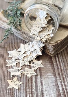 a jar filled with lots of paper cut outs sitting on top of a wooden table