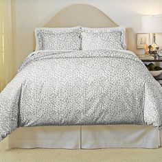 the comforter is made up with white and gray leopard print on it, along with matching pillows