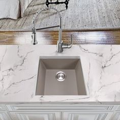 a kitchen sink sitting under a faucet on top of a marble countertop