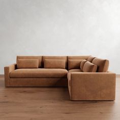 a brown couch sitting on top of a hard wood floor next to a white wall