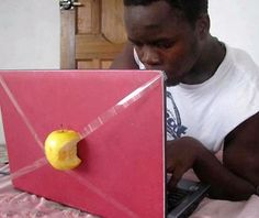 a man sitting in front of a laptop computer with an apple on the keyboard and paper airplane attached to it